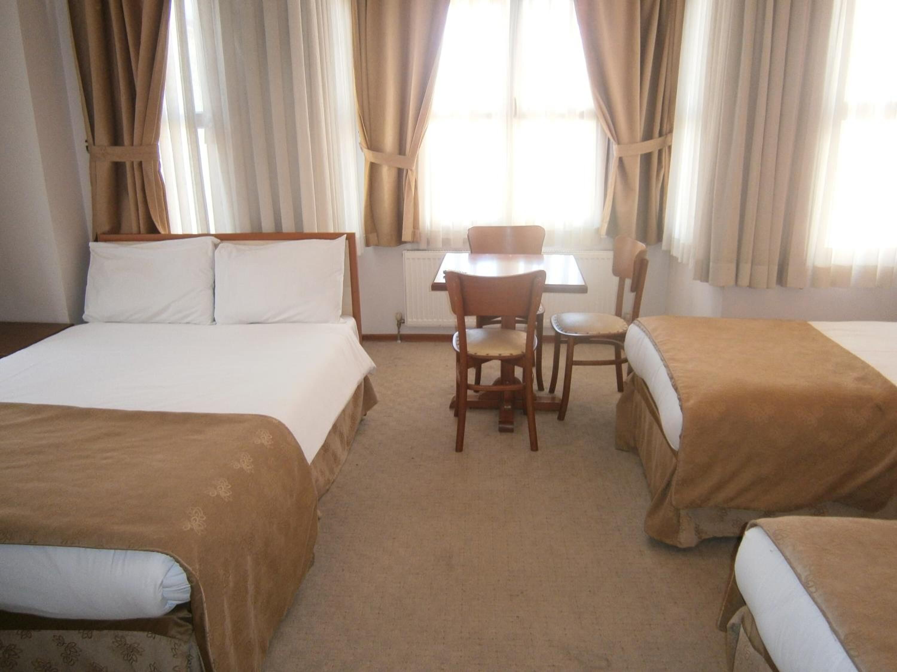 A hotel room with two beds, a small table, and chairs.