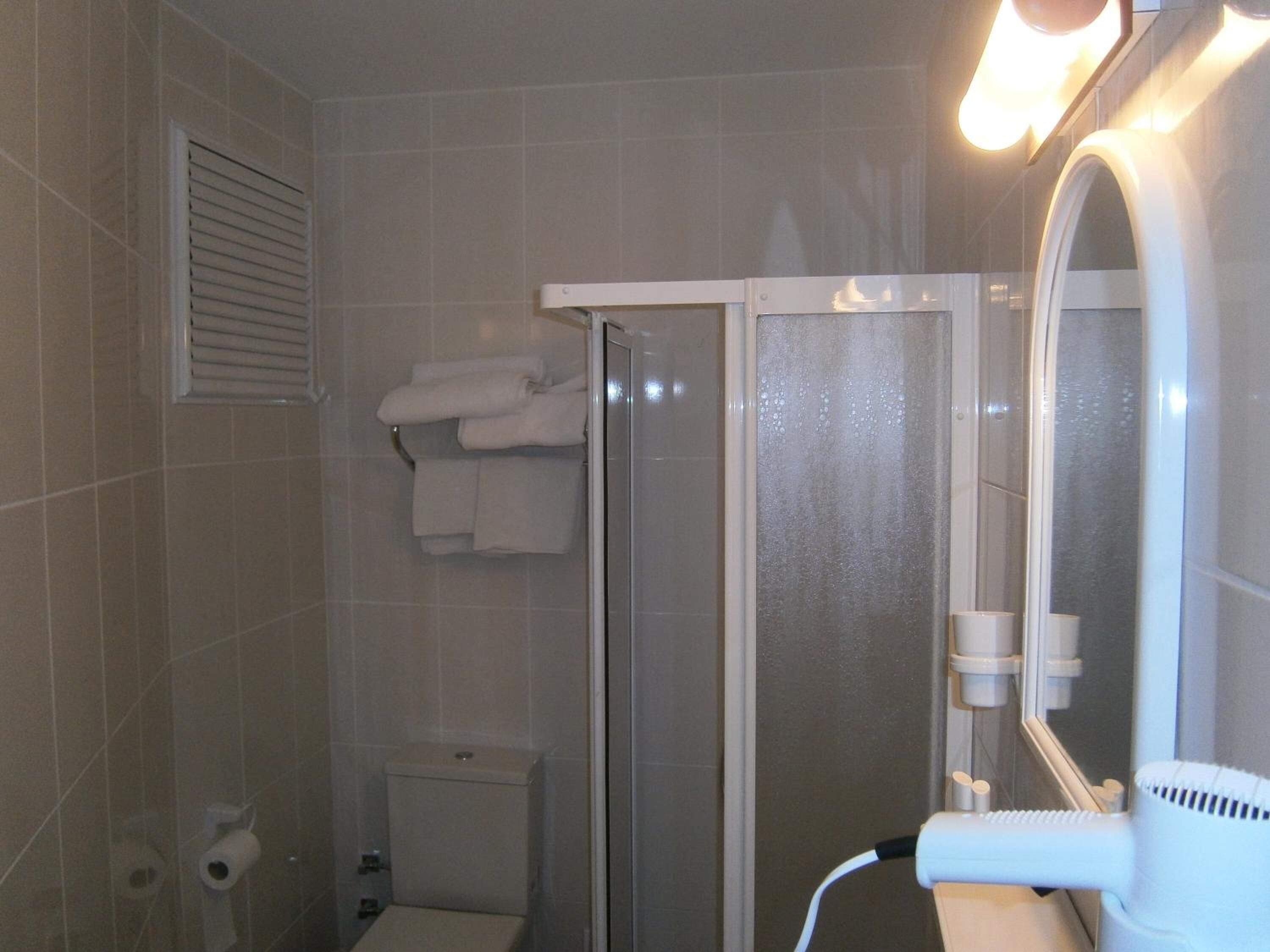 Une salle de bain comprenant des toilettes, un espace douche et un miroir.