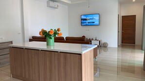 A modern kitchen with a central island, a ceiling fan, a mounted TV, and a wooden door. - Private Villa with Pool near Laguna (Choeng Thale)