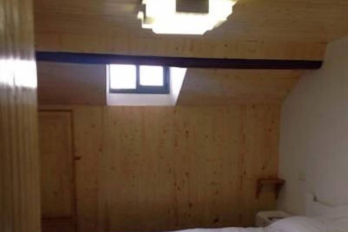 A small, single-room cabin with a sloped ceiling and a skylight.