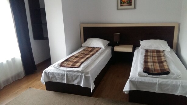A hotel room with two single beds, a nightstand, a lamp, and a framed picture on the wall.