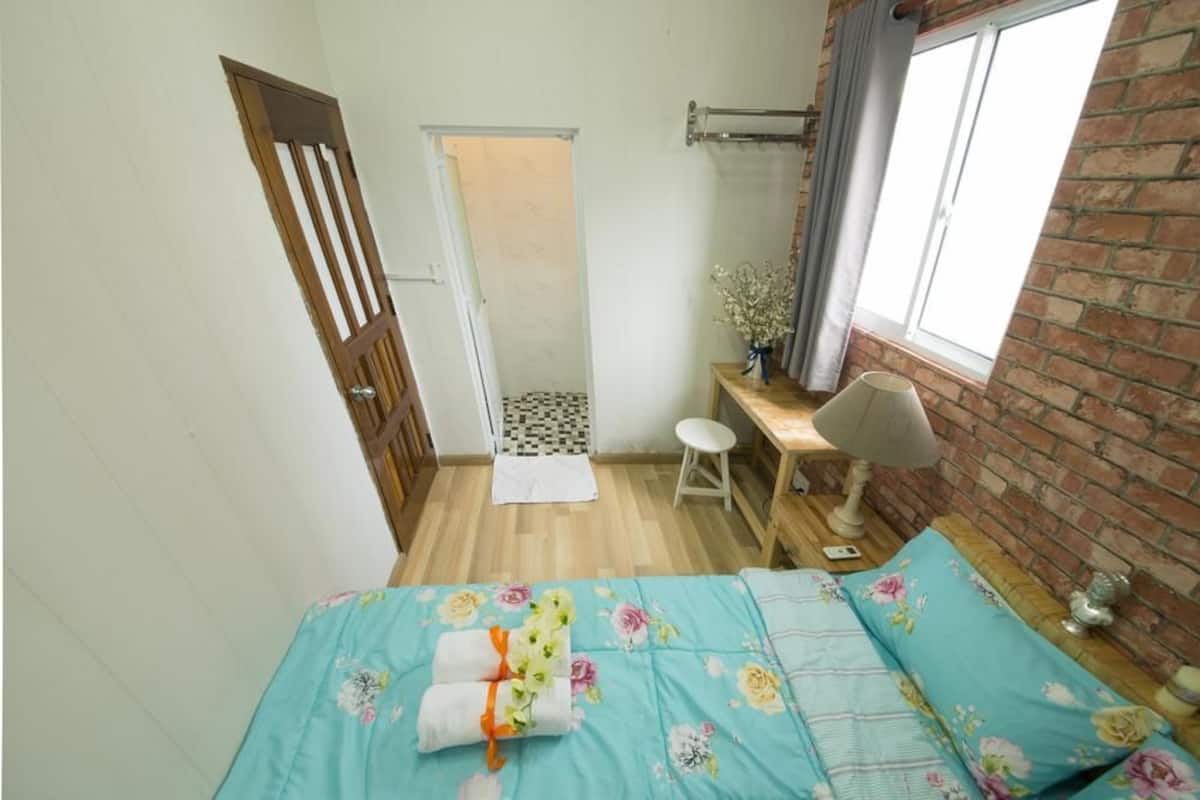 A small, cozy room with a bed, a desk, a chair, and a window.