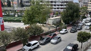 Un estacionamiento con varios autos, un edificio con balcones y un letrero que dice 'OTEL KARY'.
