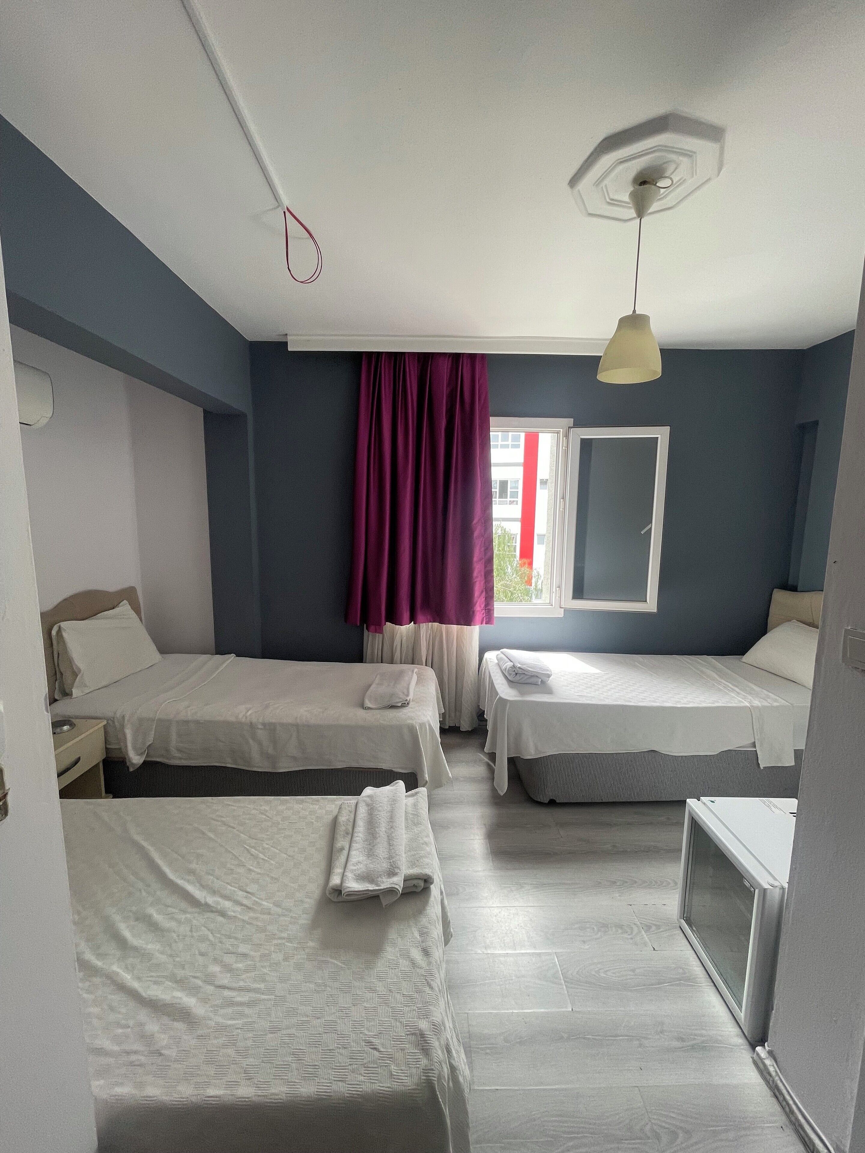 A hotel room with two beds, a TV, and a window with curtains.