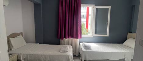 A hotel room with two beds, a TV, and a window with curtains.