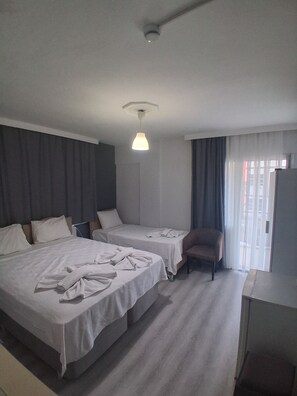 Une chambre d’hôtel avec deux lits, une chaise, un bureau et une fenêtre avec des rideaux.