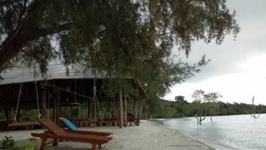 A beach with a wooden lounge chair and a thatched-roof structure. - Koh Rong Love Resort - Hostel (Koh Rong)