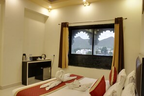 A hotel room with a bed, a desk, and a window with curtains. - The Byke Riddhi Inn (Udaipur)