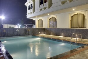 An indoor swimming pool with a stone border, a marble floor, and a balcony with ornate railings. - The Byke Riddhi Inn (Udaipur)
