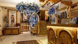 A warmly decorated interior with a wooden staircase, a Christmas tree, and a poster with a child. - Kraina Smaku (Zakopane)