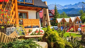 A chalet with a wooden balcony, a red slide, and a mountain backdrop. - Kraina Smaku (Zakopane)