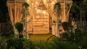 A wooden structure with a heart-shaped decoration, surrounded by greenery and string lights. - Kraina Smaku (Zakopane)
