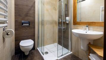 A modern bathroom with a glass-enclosed shower, a white toilet, and a sink with a mirror above it.