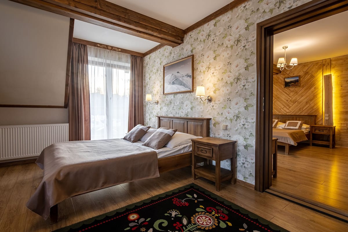 Un dormitorio con cama de madera, mesitas de noche, un espejo y una ventana con cortinas.