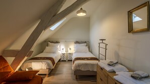 Un dormitorio acogedor en el ático con dos camas, una escalera de madera y un tragaluz.