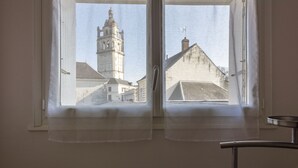 Habitación con dos ventanas que dan a un edificio histórico con una torre destacada.