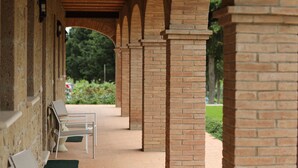A covered outdoor area with brick columns and white chairs.