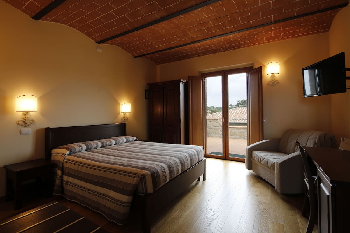 A bedroom with a bed, a desk, a chair, and a TV.