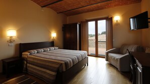 A bedroom with a bed, a desk, a chair, and a TV.