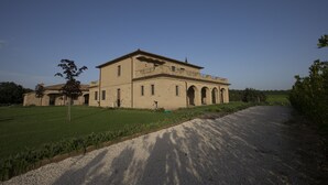 A large, historic building with a symmetrical facade, multiple arches, and a central tower.
