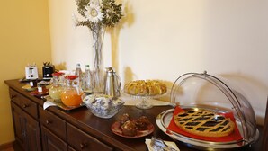 A buffet table with various food items, a vase with flowers, and a coffee maker.
