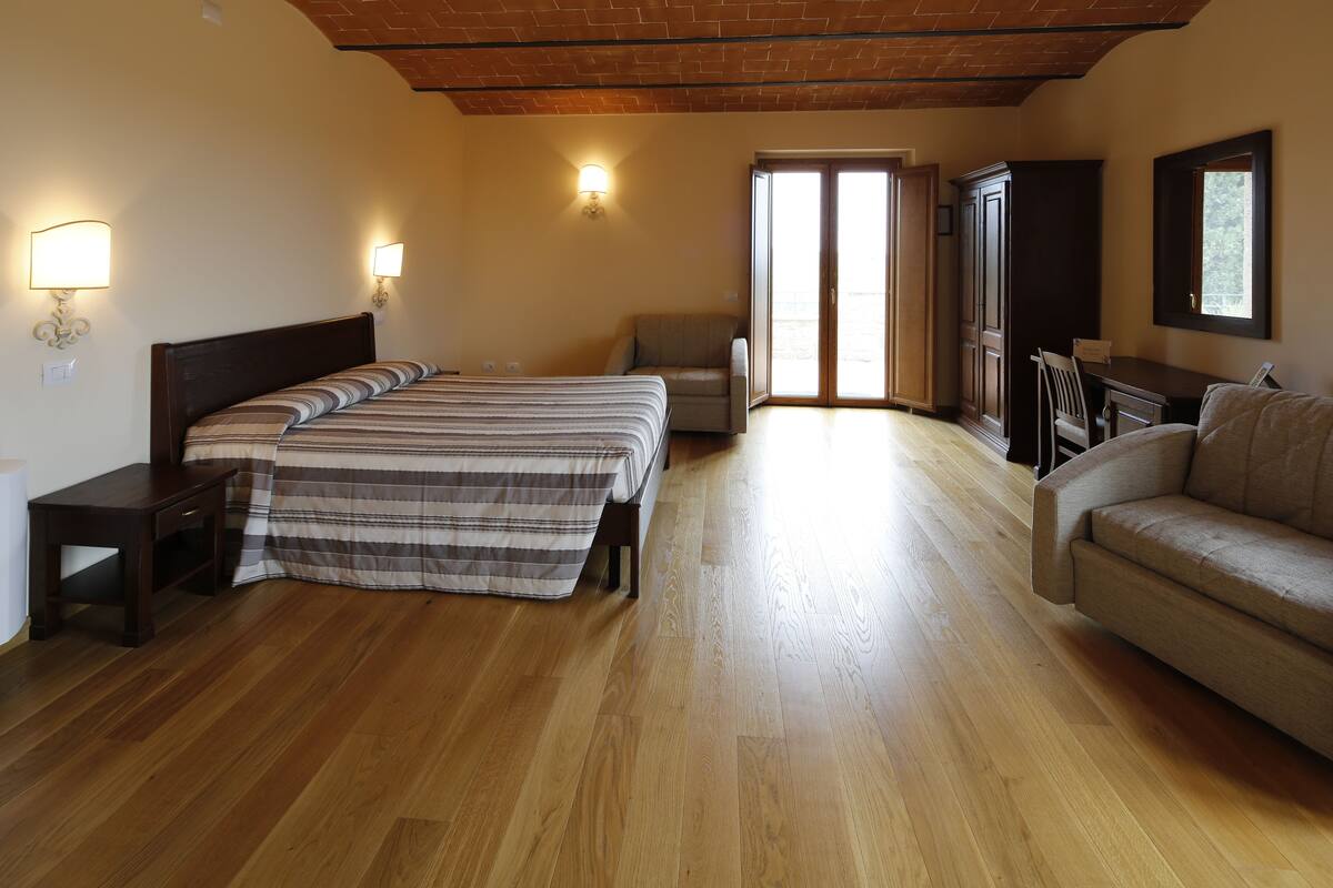 A spacious bedroom with a large bed, a sofa, a desk, and a chair.