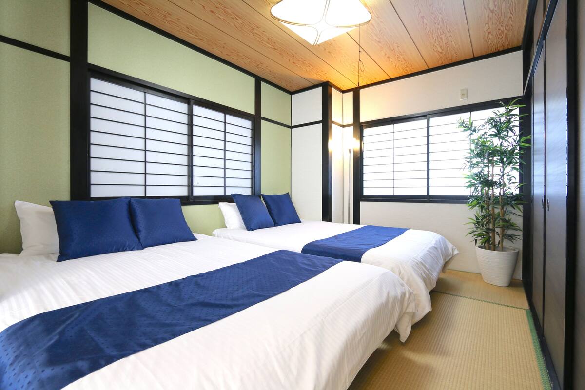 Ein Hotelzimmer mit zwei Betten, einer Zimmerpflanze und einer traditionellen Schiebetür.