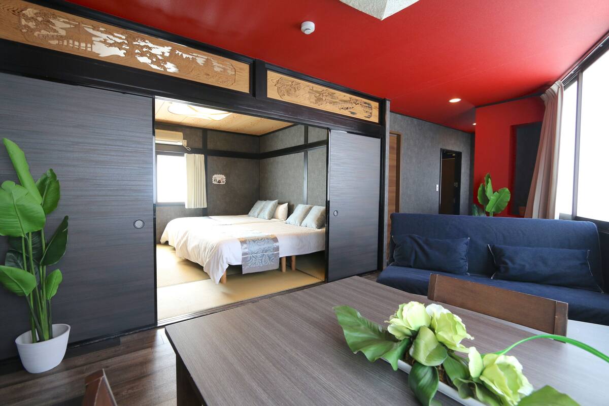Ein modernes Hotelzimmer mit einem Bett, einer Couch, einem Esstisch und einer Topfpflanze.