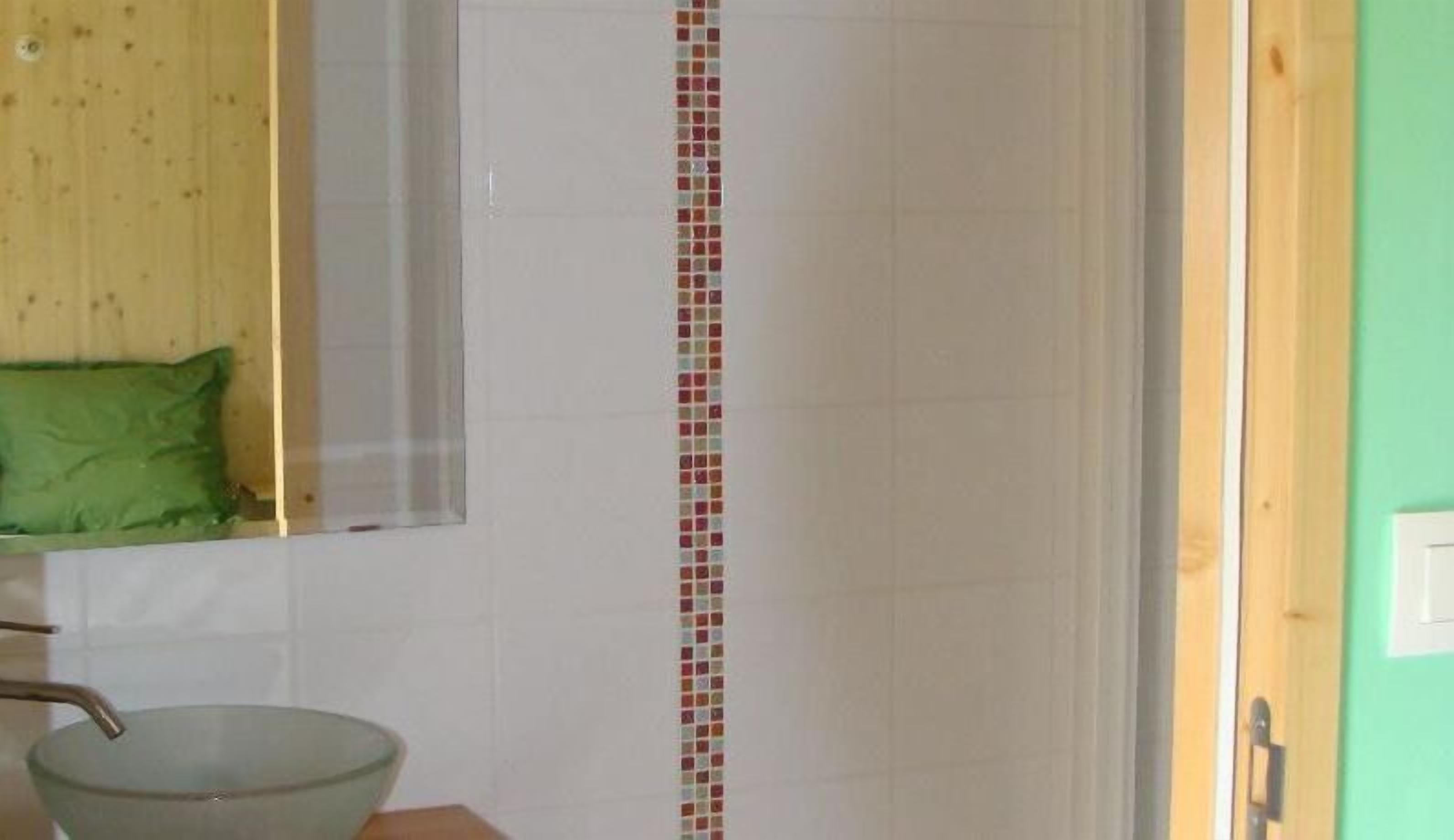 Une salle de bain avec un mur recouvert de carreaux blancs, une serviette verte et un lavabo en métal.