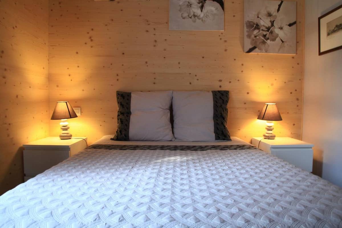A bedroom with a large bed, two bedside lamps, and a wooden headboard.