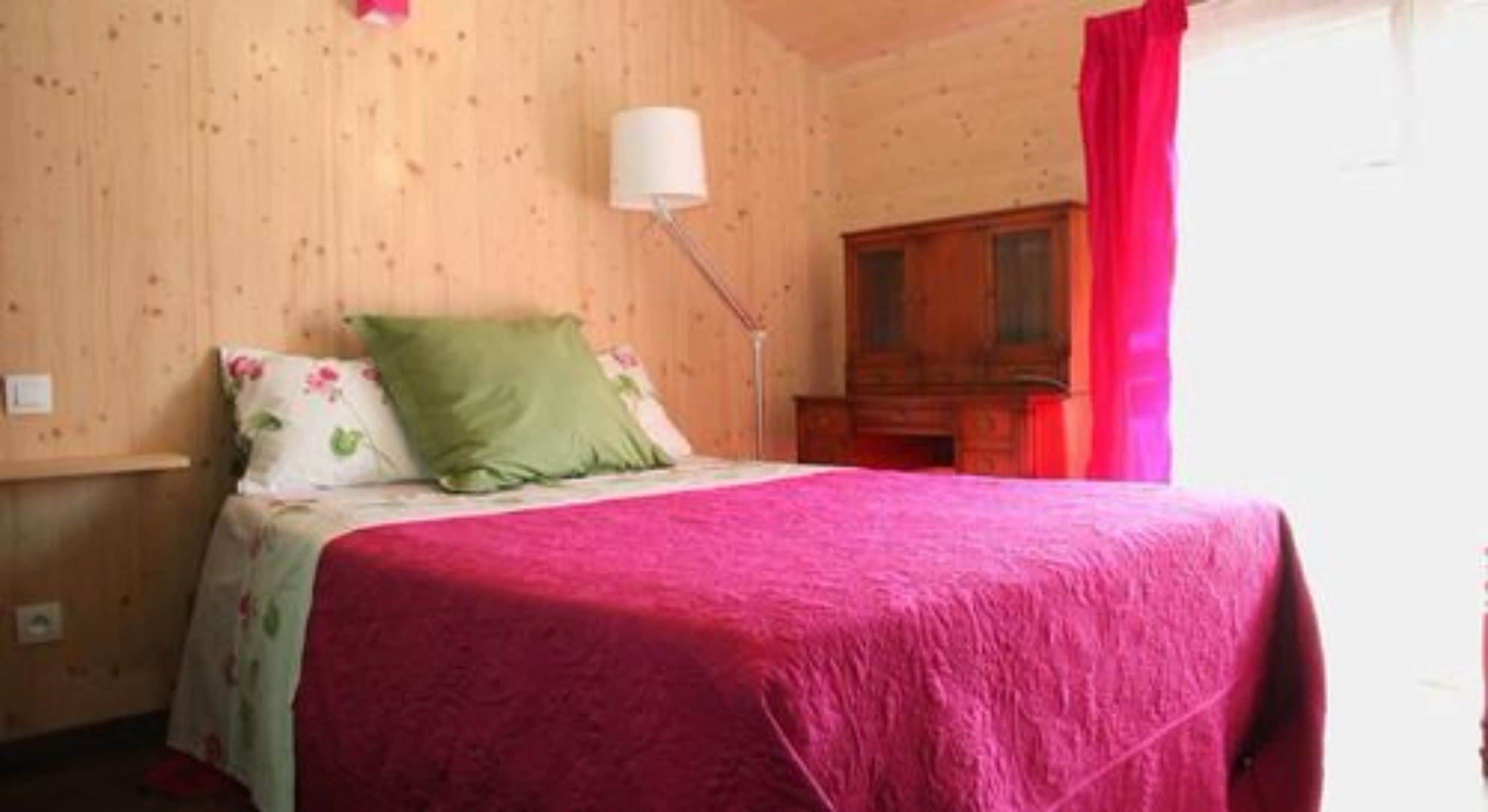 Un dormitorio con cama, mesita de noche, lámpara y armario de madera.