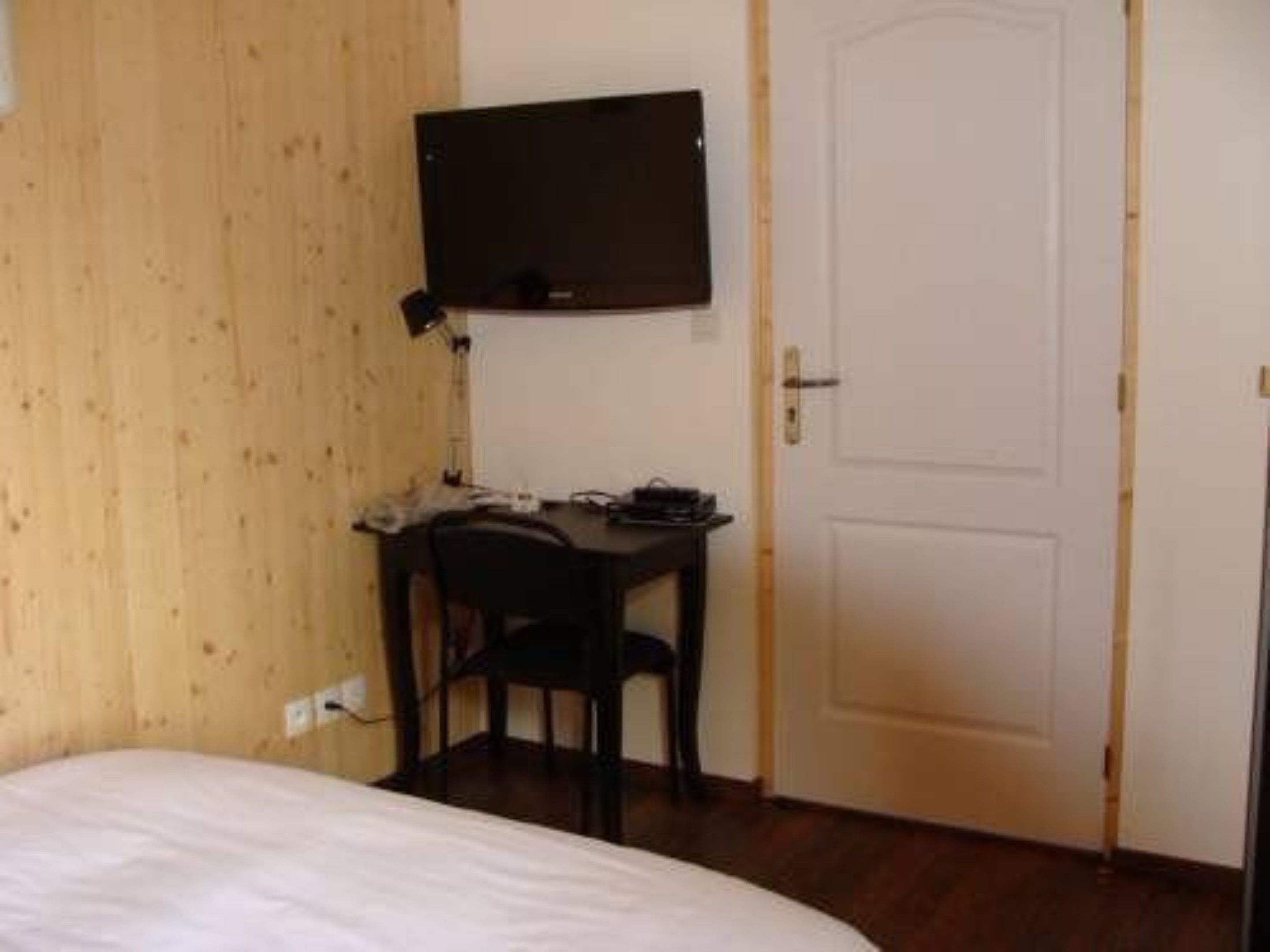 Ein kleines Zimmer mit einem Bett, einem Schreibtisch, einem Stuhl und einer Tür.