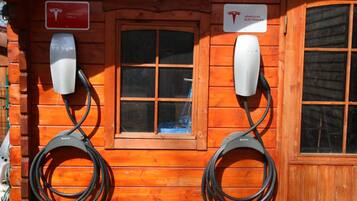 A wooden cabin with two Tesla charging stations and a window.