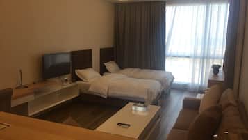 Una habitación de hotel con cama, televisor, sofá y mesa de centro.