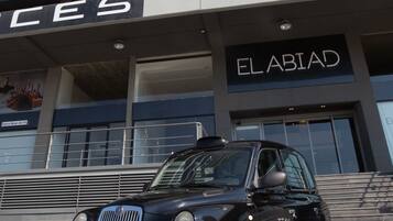 A black car parked in front of a building with a sign that reads "EL ABIAD".