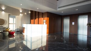 A modern lobby with a reception desk, a marble floor, and a large vase with flowers. - The Stay Furnished Apartments (Dbayeh)