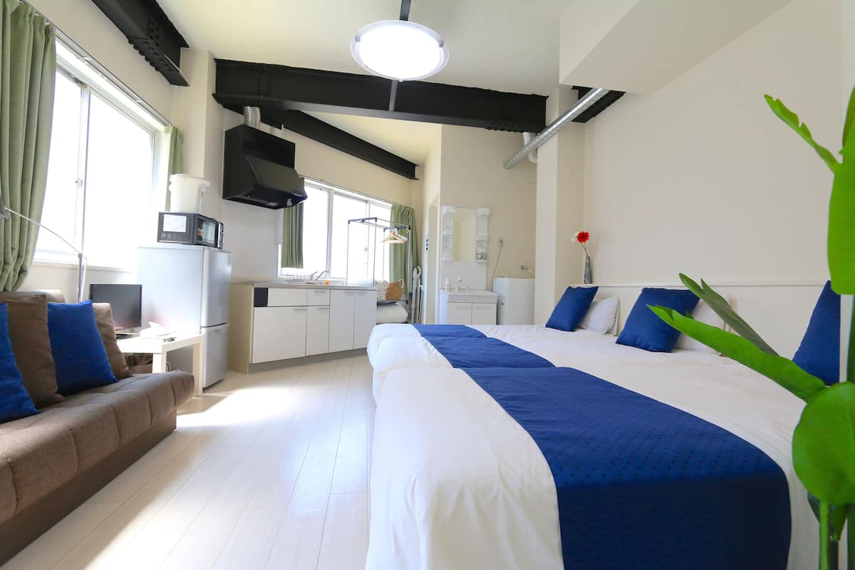 Ein modernes Hotelzimmer mit einem großen Bett, einer Couch, einer Küchenzeile und einem Badezimmer.