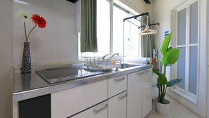 Cozinha moderna com armários brancos, pia de aço inoxidável e janela com cortinas.