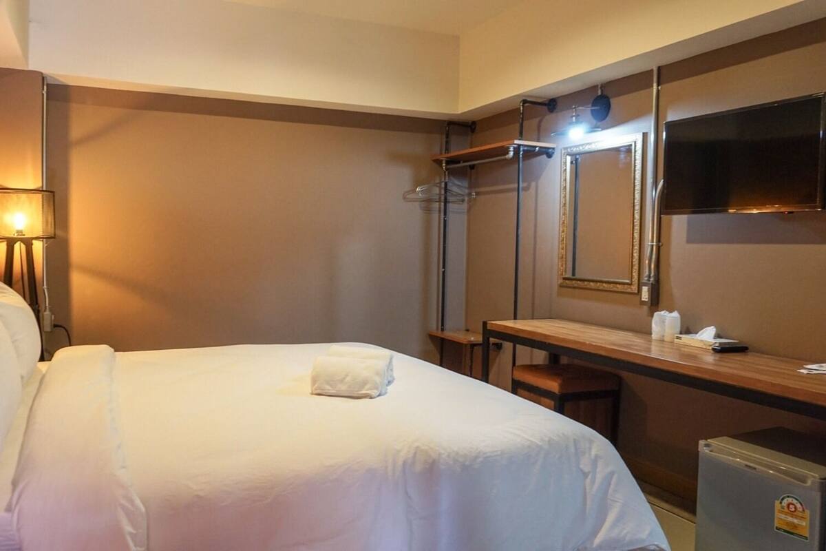 Une chambre d’hôtel équipée d’un lit, d’un bureau, d’une chaise, d’une télévision et d’un miroir.