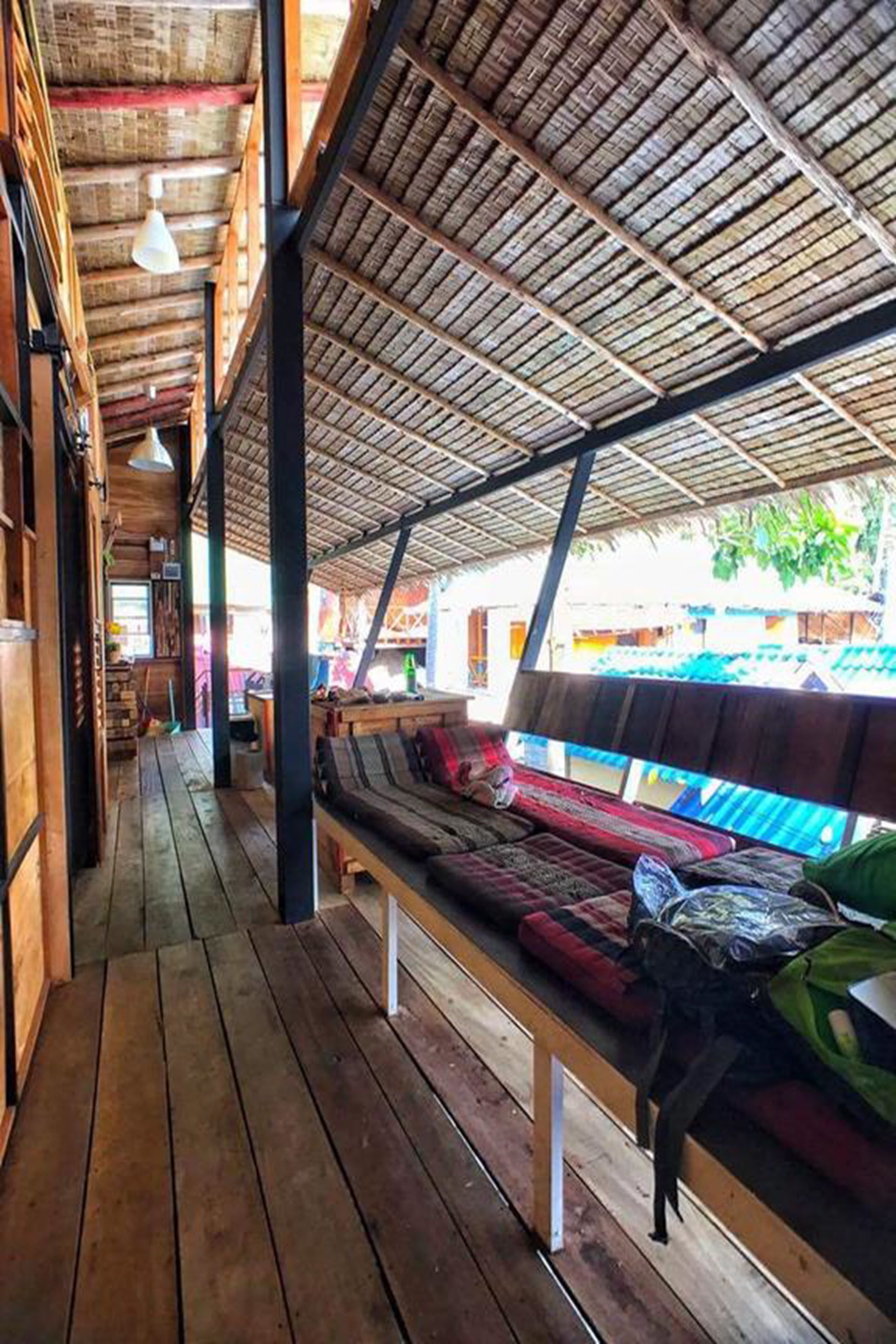 A wooden interior with a thatched roof, benches, and a view of the outside.