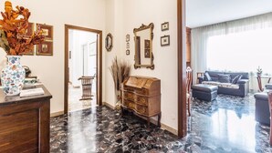 A spacious living area with a marble floor, a wooden cabinet, and a large mirror on the wall. - Montebello 7 (Bologna)
