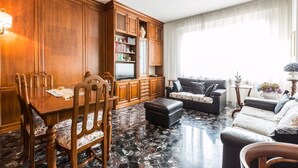 A spacious living area with a wooden dining table, chairs, a sofa, and a TV. - Montebello 7 (Bologna)