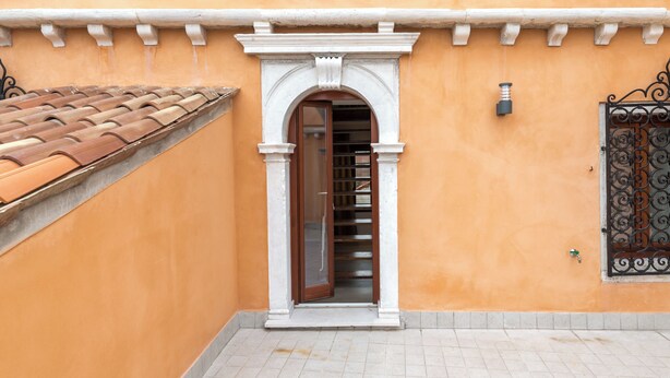 A building with a tiled roof, a doorway with an arch, and a tiled floor. - Charming Palace Corte Del Teatro (Venice)