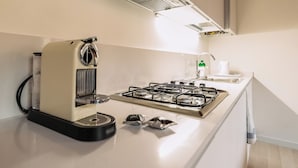 A modern kitchen with a coffee maker, gas stove, and a sink. - Charming Palace Corte Del Teatro (Venice)