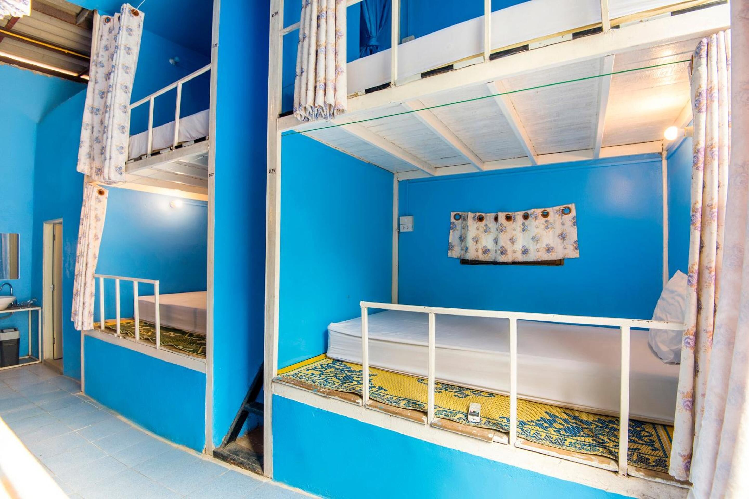 Una habitación con dos literas, una ventana pequeña y una cortina.