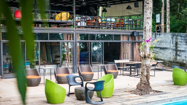 An outdoor pool area with seating and a restaurant in the background.