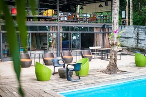 An outdoor pool area with seating and a restaurant in the background.