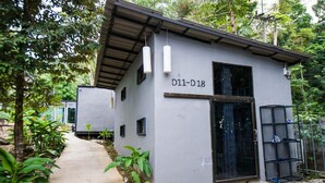 A small, modern building with a grey exterior and a metal roof. It has a sign reading "D11-D18" and a black door.