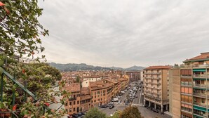 Un paisaje urbano con una mezcla de edificios históricos y modernos, una calle concurrida y vistas a colinas distantes.