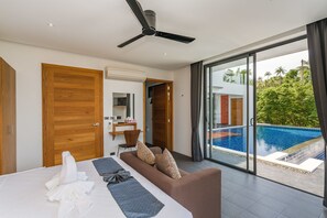 A modern hotel room with a large bed, a sofa, a ceiling fan, and a view of a swimming pool.